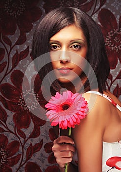 Beautiful woman with bright make up holding pink gerber flower