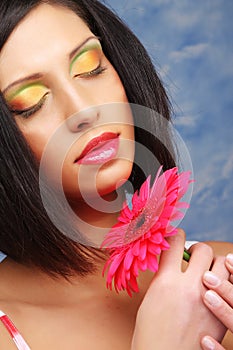 Beautiful woman with bright make up holding pink gerber flower