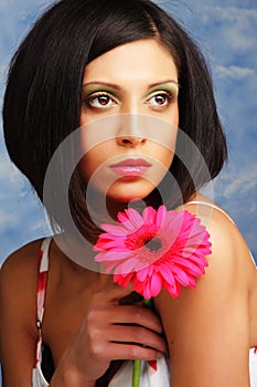 Beautiful woman with bright make up holding pink gerber flower