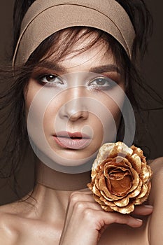 Beautiful woman with a bright make-up and perfect skin with gold flowers in her hand . Beauty face.