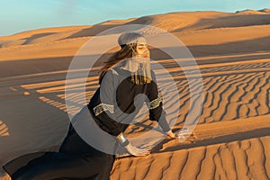 Beautiful woman in brilliant Burqa mask among the Dubai desert at sunset timeArabian style.