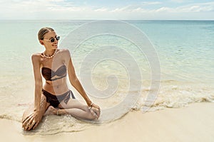 Beautiful woman in brown fashionable bikini enjoying sunny weather at the tropical beach. Freedom and carefree concept
