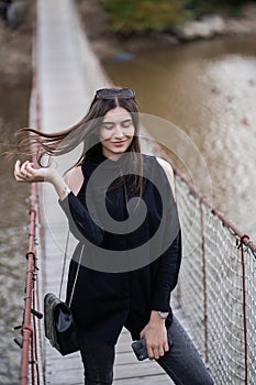 Beautiful woman with brunette hair in dark clothes and sunglasses. Fashion street photography. Fashion model is posing