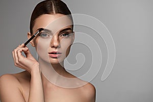 Beautiful Woman Brushing Eyebrows With Brow Tool photo