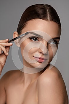 Beautiful Woman Brushing Eyebrows With Brow Tool photo