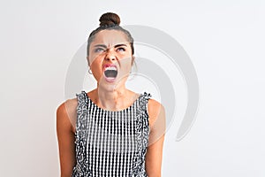 Beautiful woman with bun wearing casual dresss standing over isolated white background angry and mad screaming frustrated and
