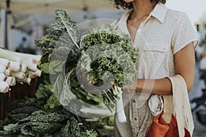 Beautiful woman buying kale at a farmers market