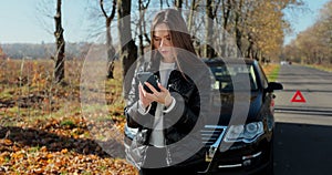 Beautiful woman calling, texting car assistance services standing by breakdown automobile on the roadside.