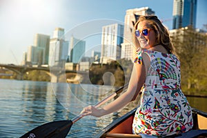 A beautiful woman in a canoe rowing on Colorado river lake, happy, joyful in Austin Texas in America