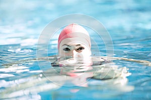 Beautiful woman cap smiling looking to camera at border of swimming pool