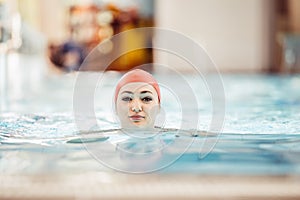 Beautiful woman cap smiling looking to camera at border of swimming pool