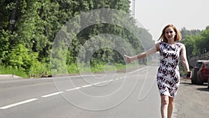 Beautiful woman catching car on a road. girl walking along the road