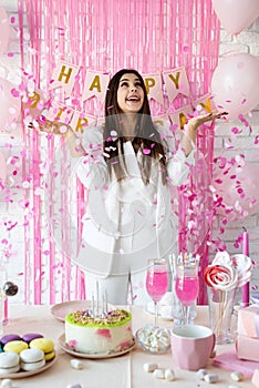 Beautiful woman celebrating birthday party throwing pink confetti