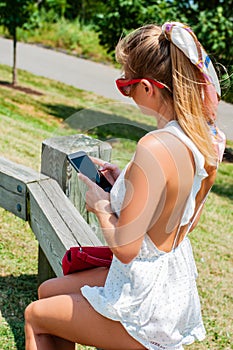 Beautiful woman with cellphone having a rest in the park.