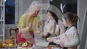 Beautiful woman and charming girls cooking tasty dinner at home indoors on Easter Sunday. Medium shot of happy