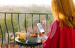 Woman chatting on phone at breakfast on terrace