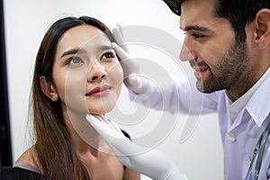 Beautiful woman check skin and face with doctor before plastic surgery in the clinic. Beautician touching and looking at woman