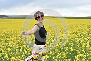 Beautiful woman cheering in rapeseed field and enjoying summer