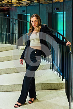 Beautiful woman in classic suit on spiral staircase holding bannister