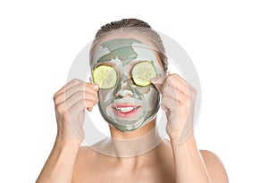 Beautiful woman with clay mask on her face holding cucumber slices