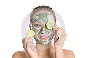 Beautiful woman with clay mask on her face holding cucumber slices