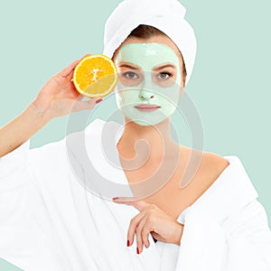 Beautiful woman with clay mask on pastel green background. Beauty and spa