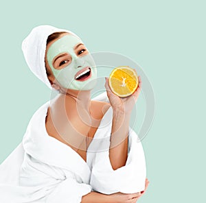 Beautiful woman with clay mask on pastel green background. Beauty and spa