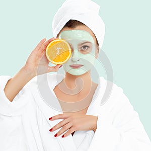 Beautiful woman with clay mask on pastel green background. Beauty and spa