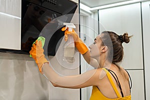 Beautiful woman cleaning her kitchen hood from dust