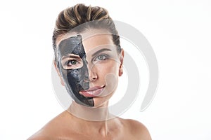 A beautiful woman with a cleansing black mask on one side of her face. Isolated on white with copy space