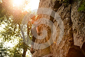 Beautiful Woman Climbing on the Rock at Foggy Sunset in the Mountains. Adventure and Extreme Sport Concept