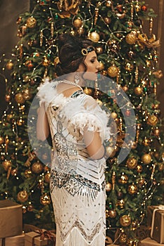 Beautiful woman close up on the decorated fir-tree background. Gatsby style