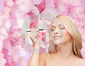 Beautiful woman with closed eyes and makeup brush