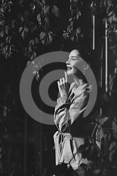 beautiful woman in coat by hedge braided with autumn vines. black and white.