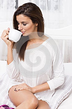 Beautiful woman with coffee on the bed