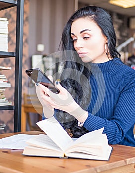 Beautiful woman at coffee shop. Person side view, send message by smartphone. Student reading books for exam in library