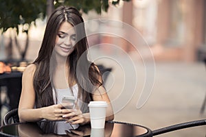 Beautiful Woman In Coffee Shop Sending Sms On Smartphone.