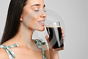 Beautiful woman with cold kvass on light grey background, closeup. Traditional Russian summer drink