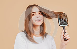 Beautiful woman combs her healthy hair. Combing healthy long straight female hair, close up. Attractive gorgeous