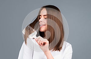 Beautiful woman combs her healthy hair. Combing healthy long straight female hair, close up. Attractive gorgeous