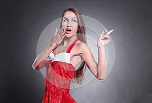 Beautiful woman in costume of Santa Claus pointing to copy space
