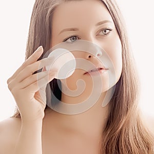 Beautiful woman with cotton pad, perfect skin and shiny hair as make-up, health and wellness concept. Face portrait of