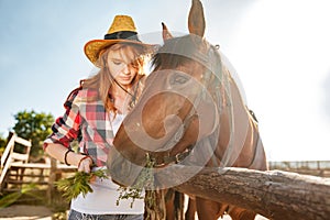 Beautiful woman cowgirl taking care and givivn food to horse