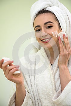 Beautiful woman  with cream in hands doing make up. Skin care clean