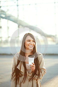 Beautiful Woman With Cup Of Coffee Walking On Street. Portrait Of Attractive Young Female In Stylish Office Clothes Holding Cup Of