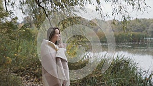 Beautiful woman with cup of tea enjoys a view on an autumn river