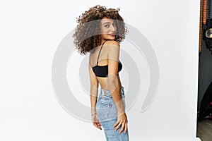 Beautiful woman with curly afro hair posing on a white isolated background smile happiness in jeans and black top