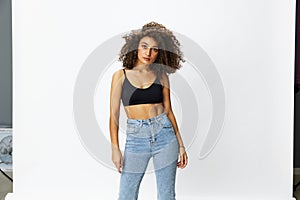 Beautiful woman with curly afro hair posing on a white isolated background smile happiness in jeans and black top