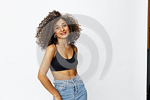 Beautiful woman with curly afro hair posing on a white isolated background smile happiness in jeans and black top