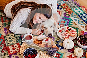 beautiful woman and cute golden retriever dog enjoying healthy breakfast at home, lying on the floor. healthy breakfast with tea,